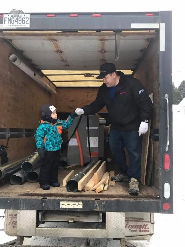 Un technicien Thermomax et un jeune enfant dans la boîte d'un camion de service