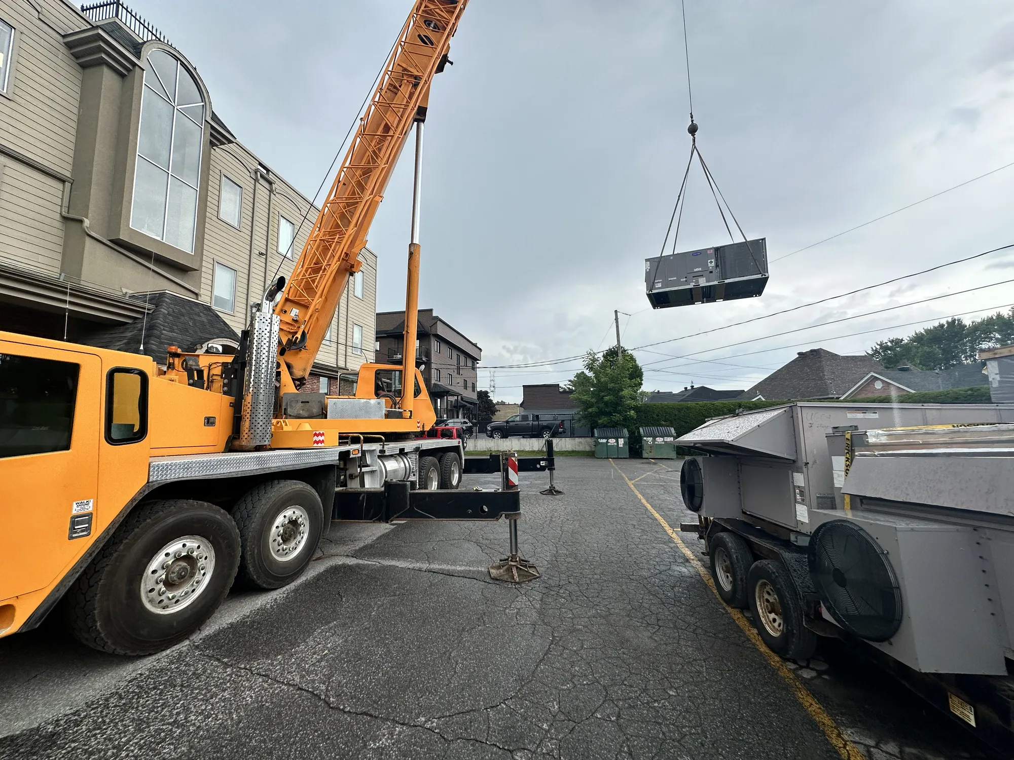 Grue soulevant une unité de toit au-dessus d'un immeuble
